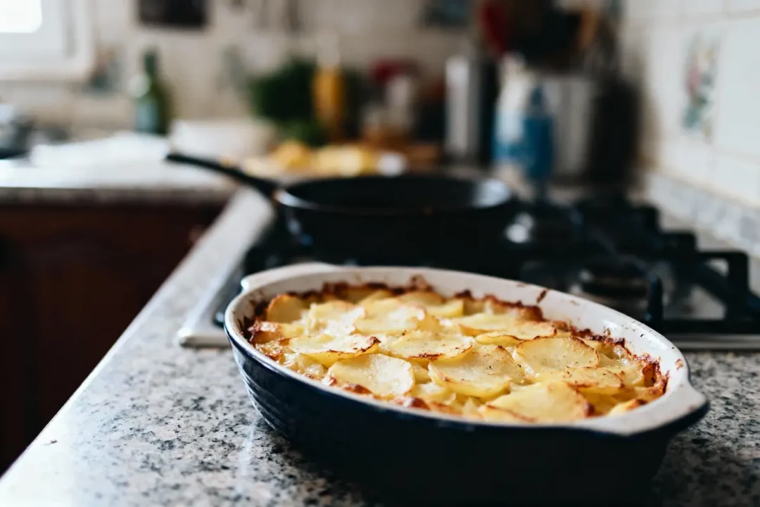 Plat de gratin de pommes de terre doré sur une cuisinière dans une cuisine.