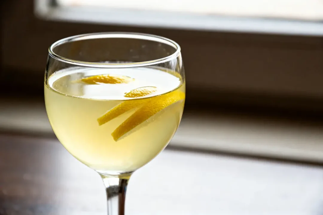 Verre de limoncello depré avec zestes de citron posé sur une table en bois