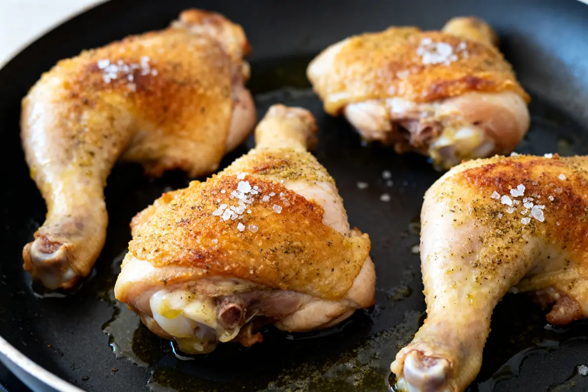 Quatre cuisses de poulet dorées et salées illustrant une recette de cuisse de poulet au four croustillante