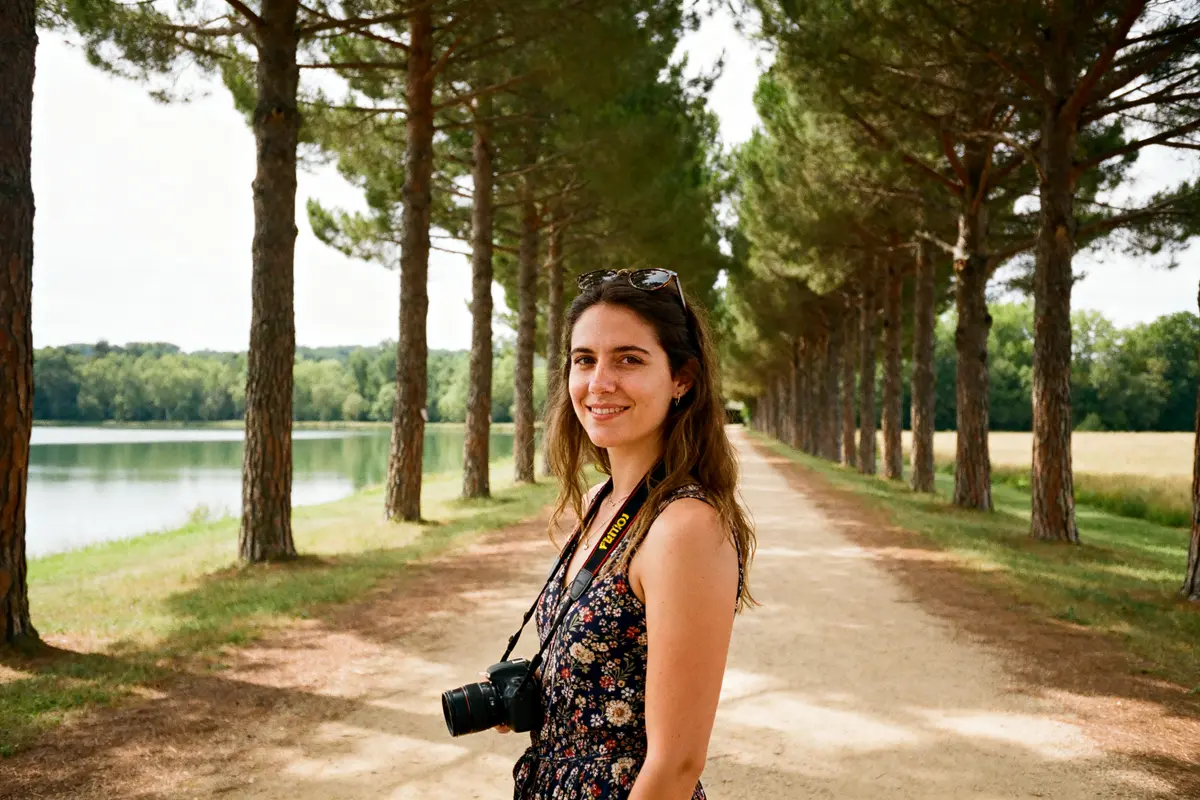 Femme souriante dans une allée boisée au Domaine de Preissac près d'un étang