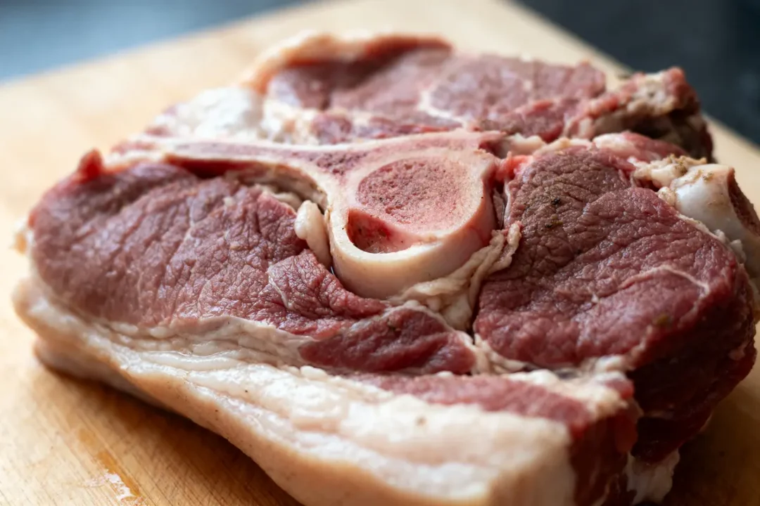 Gros plan d'une pièce de viande pour carbonnade avec os sur une planche en bois